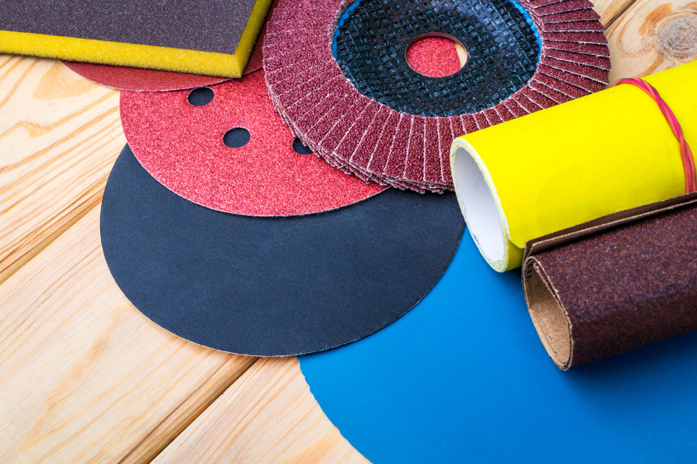 Set of abrasive tools and sandpaper different colors on wooden background